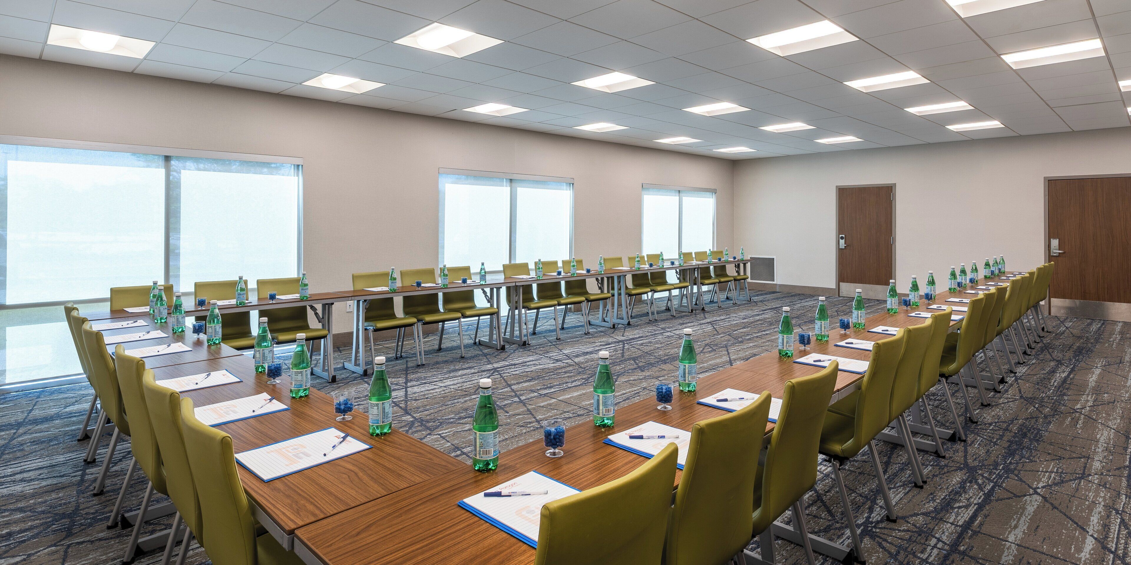 A conference room with multiple tables, chairs, and water bottles.