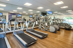 Un gimnasio con cintas de correr, elípticas y pelotas de ejercicio.