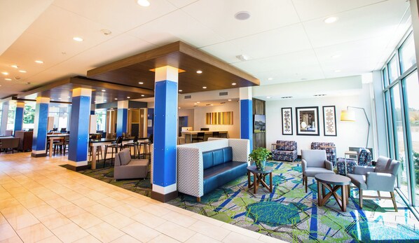 A hotel lobby with a reception desk, seating area, and a large window providing a view. - Holiday Inn Express & Suites Greenwood Mall by IHG (Greenwood)