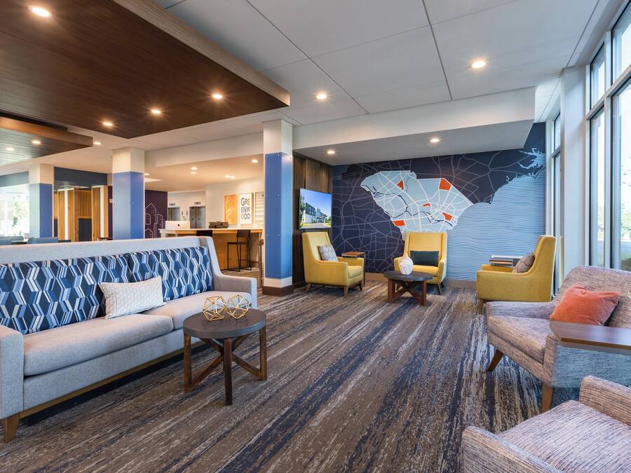 Um lobby moderno com um sofá, poltronas e uma mesa de centro.
