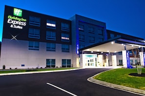 Edificio de Holiday Inn Express & Suites con diseño moderno, amplios ventanales y una entrada bien iluminada.