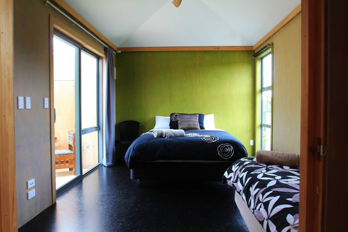 A bedroom with a bed, a chair, and a window.