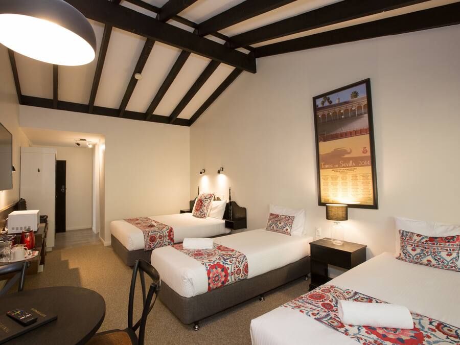 A hotel room with two beds, a desk, a chair, a TV, and a poster on the wall.