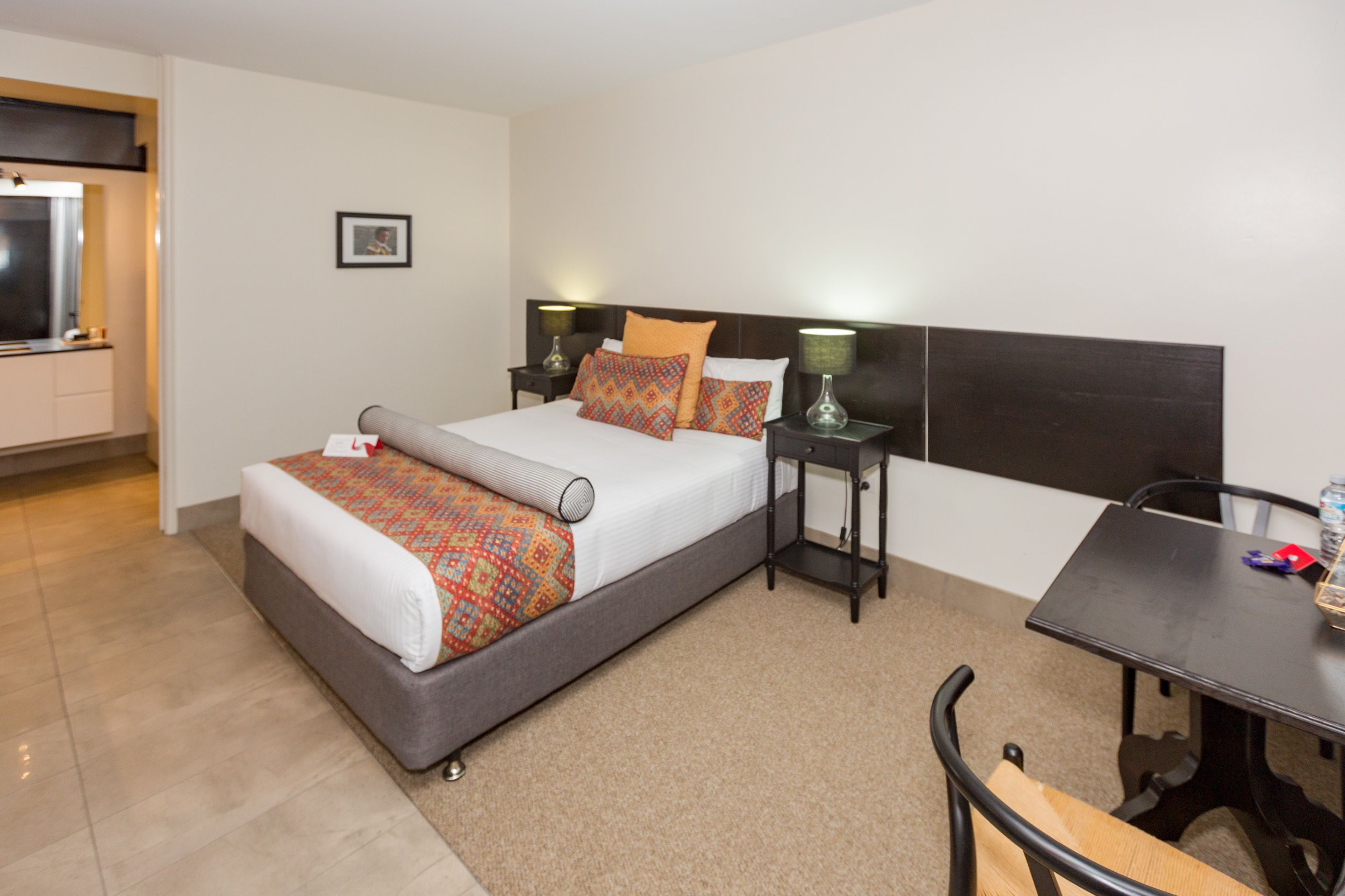 Een hotelkamer met een bed, nachtkastjes, een bureau en een stoel.