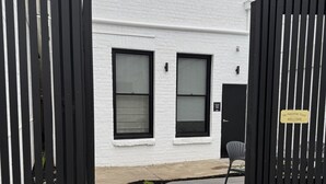 A white building with two windows, a black gate, and a sign that says 'The Porcupine Place Welcome.' - The Matador (Sale)