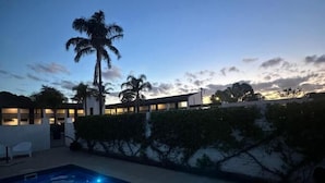 A swimming pool with a view of a building and palm trees at dusk. - The Matador (Sale)
