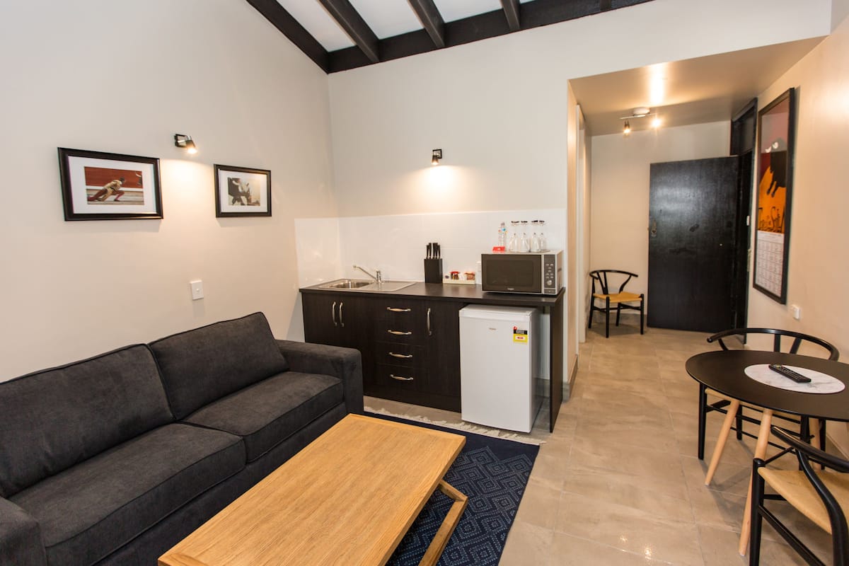 Un espacio habitable compacto con sofá, mesa de centro, kitchenette y comedor con mesa y sillas.