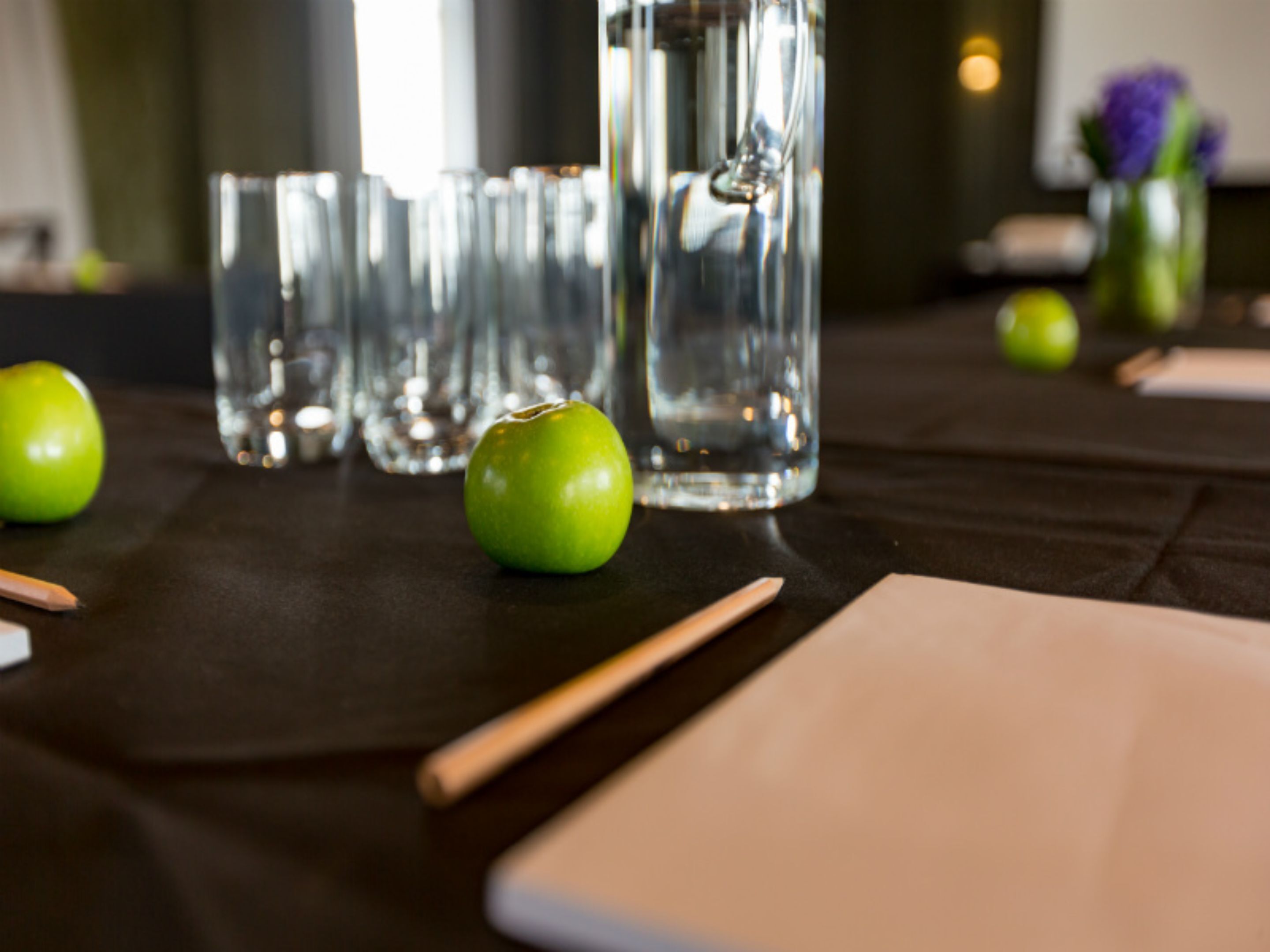 A table with glasses, a green apple, and a napkin.