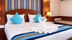 Une chambre d’hôtel avec un grand lit, une tête de lit en bois, un climatiseur fixé au mur, une lampe de chevet et un banc.