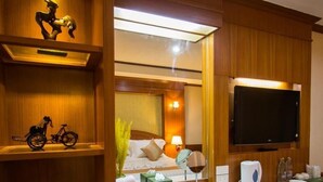Une chambre d’hôtel équipée d’une coiffeuse en bois, d’un téléviseur à écran plat fixé au-dessus du comptoir, d’un petit réfrigérateur et d’une poubelle.