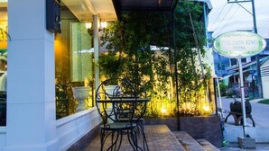 Un espace extérieur aménagé avec une terrasse couverte, une table et des chaises, ainsi qu’une enseigne indiquant l’hôtel « The Lion King ».