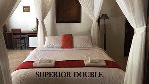 Quarto com uma cama identificada como 'SUPERIOR DOUBLE', uma escrivaninha, cadeira e abajur.