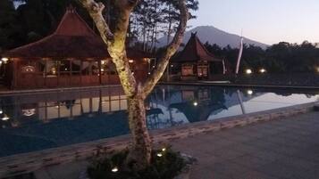 A poolside area with a reflection of a building and a mountain in the background.