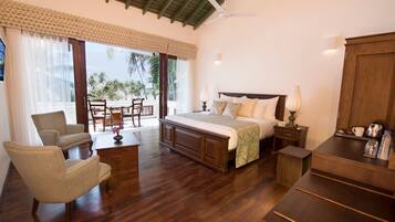 A spacious bedroom with a large bed, wooden furniture, a ceiling fan, and a view of palm trees through the window.