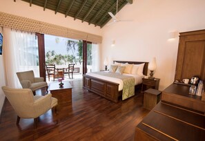 A spacious bedroom with a large bed, wooden furniture, a ceiling fan, and a view of palm trees through the window. - Villa 46 (Hikkaduwa)