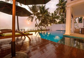 Una piscina al aire libre, sombrillas, sillones reclinables de piscina
