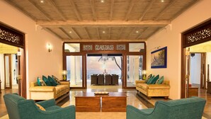 A spacious living area with two sofas, a coffee table, and a view of the beach through large windows. - Villa 46 (Hikkaduwa)