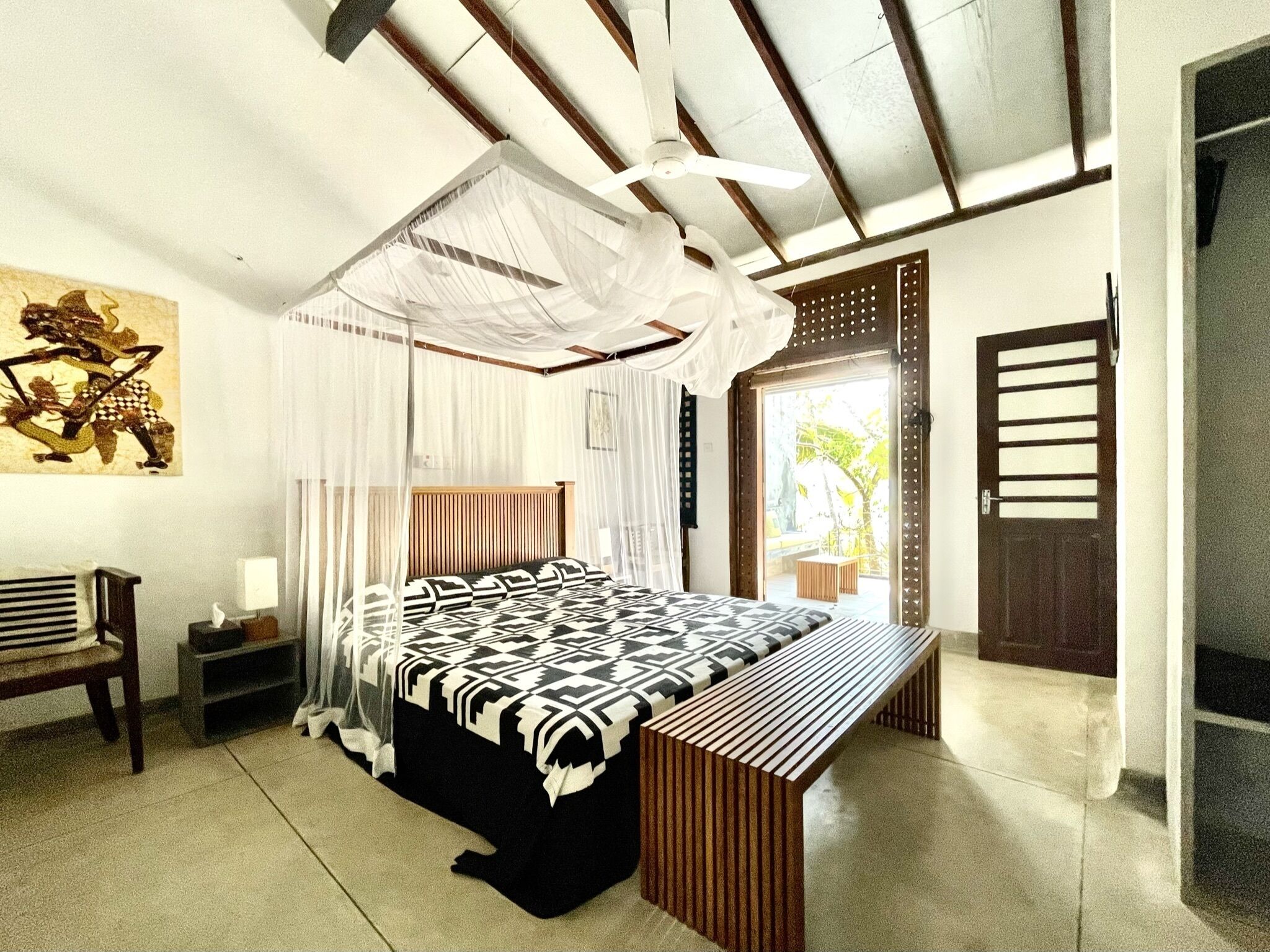 A bedroom with a bed, bedside table, and a bench.