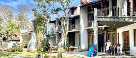 A courtyard with a small pond, outdoor seating, and a building with multiple balconies.