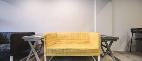 A room with a yellow sofa, a black sofa, and a table.