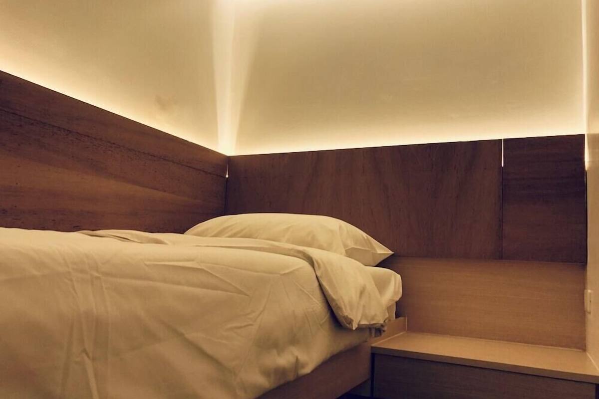 A single bed with a wooden headboard and a bedside table in a hotel room.