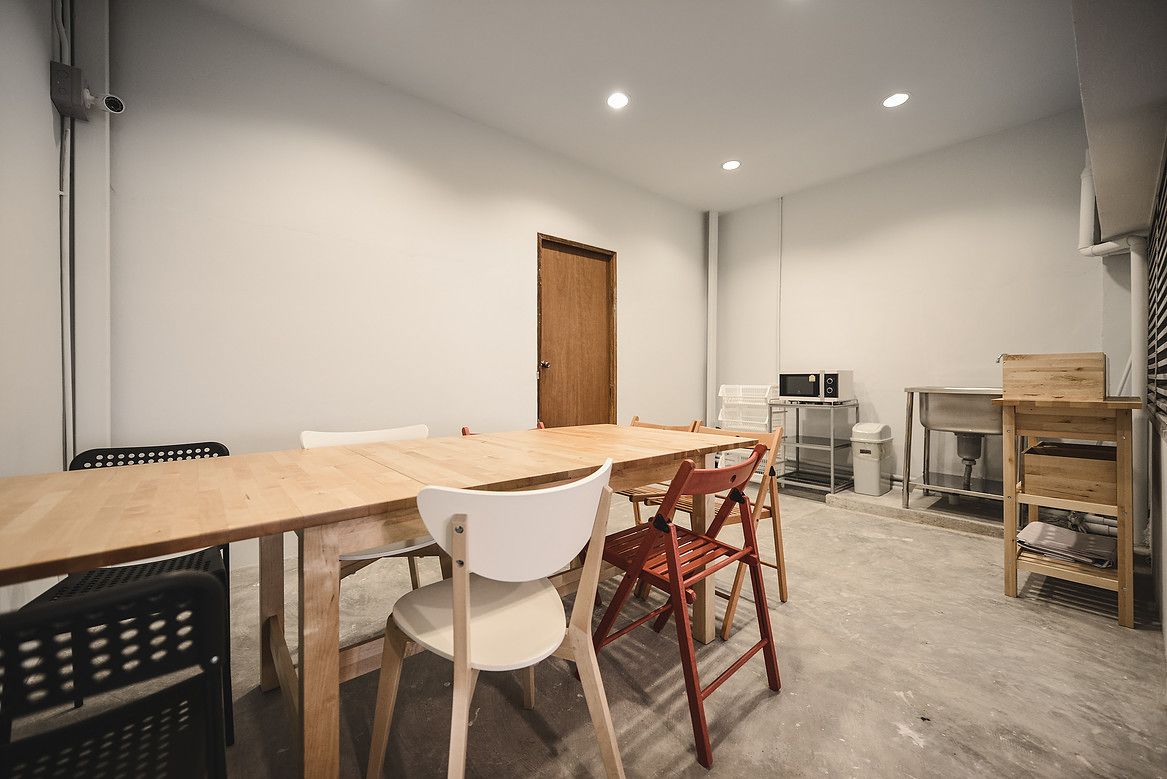 Une salle de conférence avec une longue table, plusieurs chaises, une porte et un coin cuisine.