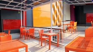 A rooftop terrace with orange wicker furniture and a glass balustrade. - Liberta Hub Singosari Malang (Malang)