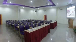 A conference room with rows of purple chairs, a long table with a red tablecloth, and a projector screen on the wall. - Liberta Hub Singosari Malang (Malang)