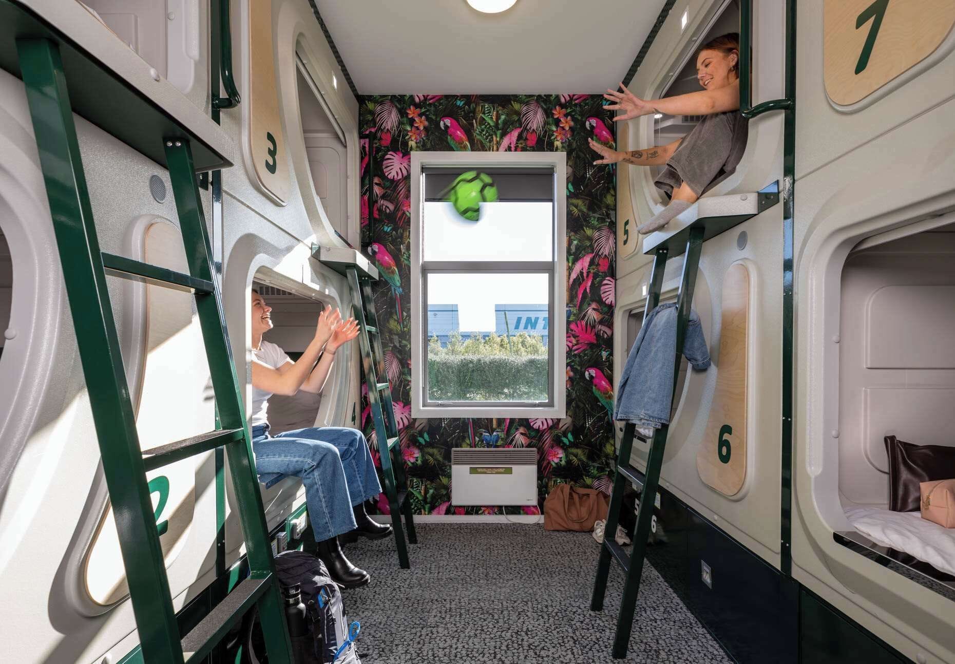 Un vagón de tren compacto con literas, compartimentos numerados y una ventana con vistas a la vegetación.