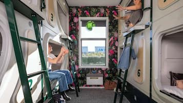 Un vagón de tren compacto con literas, compartimentos numerados y una ventana con vistas a la vegetación.