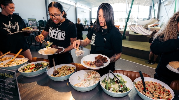 Un groupe de personnes est réuni autour d’un buffet où différents plats sont présentés dans des plats.