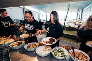 Un groupe de personnes est réuni autour d’un buffet où différents plats sont présentés dans des plats.