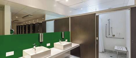 Une salle de bain moderne avec deux lavabos, un grand miroir et un espace douche.