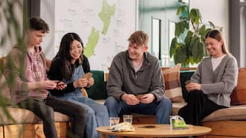 A group of people sitting on a couch and a round table with a map and snacks.