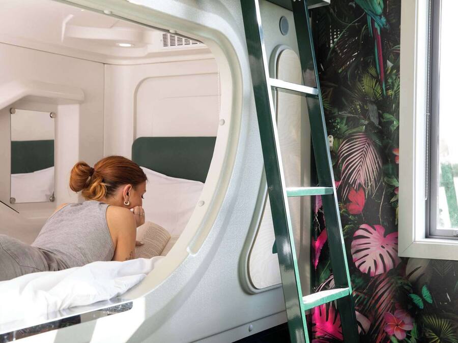 Quarto compacto e moderno com beliche e janela com painel de tema tropical.
