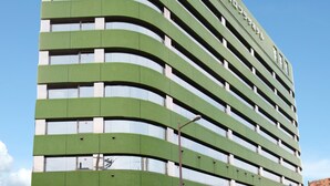 Ein mehrstöckiges Gebäude mit einer gewölbten Fassade, das eine Reihe von Balkonen und Fenstern aufweist.