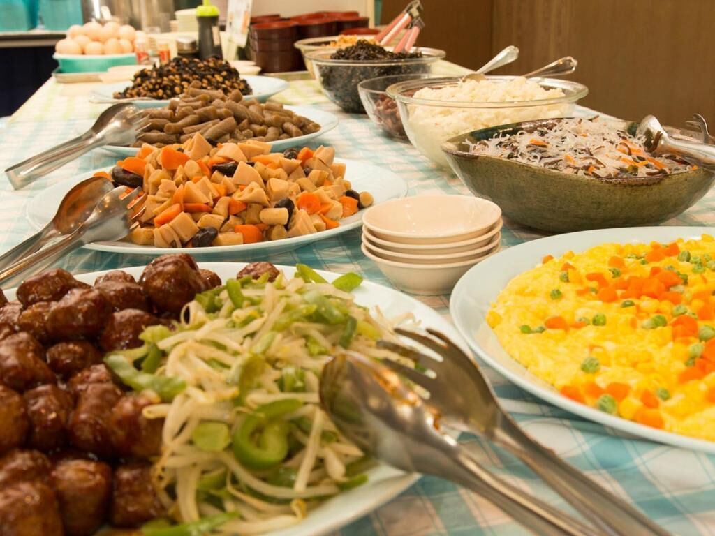 A buffet table with various dishes including meatballs, bean sprouts, and a rice dish.