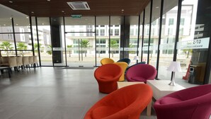 Eine moderne Hotelhalle mit großen Fenstern, bunten Stühlen und einem sauberen, gefliesten Boden.