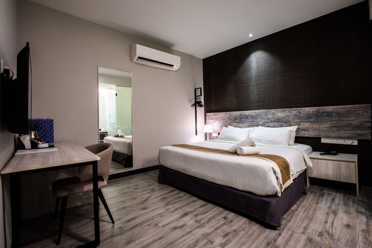 Una habitación de hotel con cama, escritorio, silla y televisor de pantalla plana.