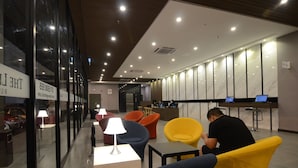 Eine moderne Lobby mit Sitzbereichen, einem Empfangstresen und einem gut sichtbaren Schild mit Kontaktinformationen.
