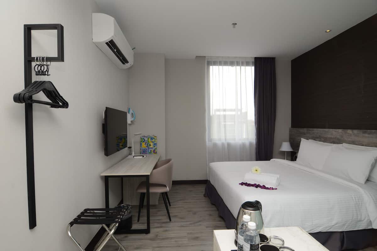Habitación de hotel con cama, escritorio, silla y aire acondicionado instalado en la pared.