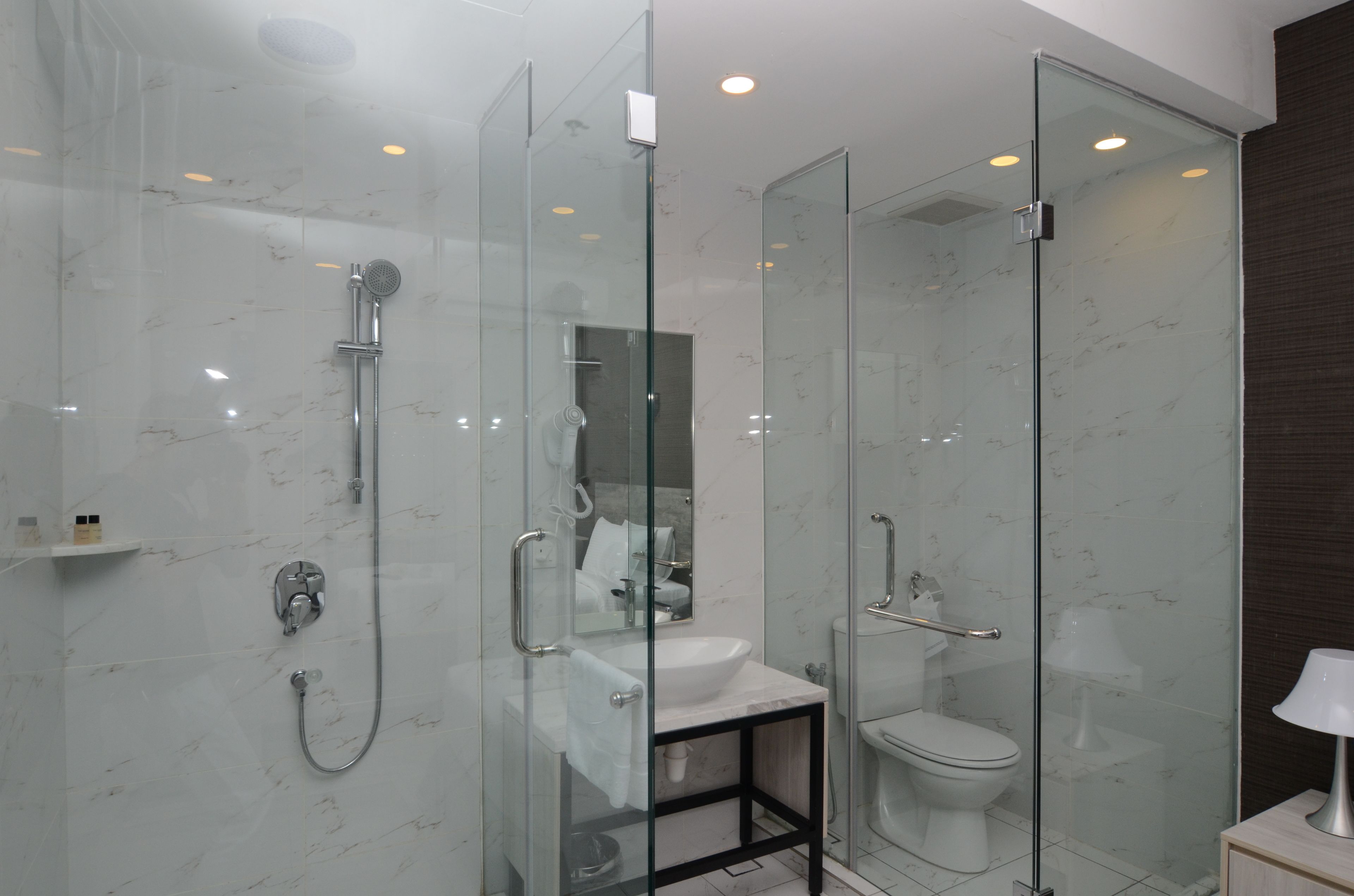 A modern bathroom with a glass-enclosed shower, a white sink, and a toilet.