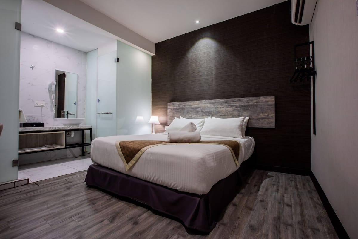 Una habitación de hotel moderna con una cama grande, una tocador con espejo y una pared de acento oscura.
