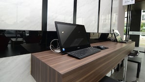 Ein Laptop auf einem Holztisch in einem modernen Büro mit Marmorwänden und einem Schild, das einen Internetbereich kennzeichnet.