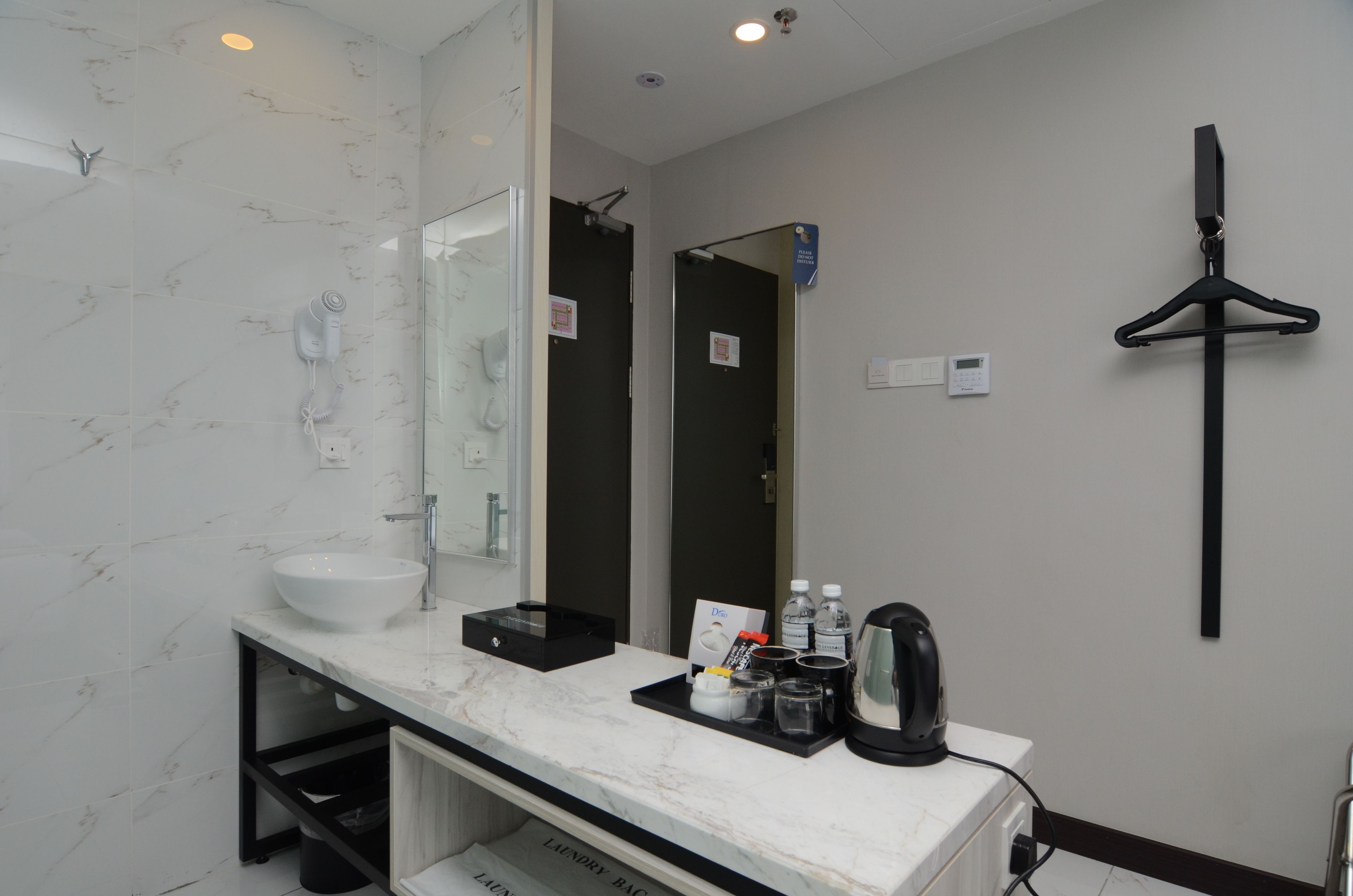 A modern bathroom with a marble sink, a large mirror, a black towel rack, and a black tray with toiletries.