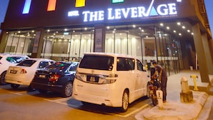 Ein Hotel mit einem Schild, auf dem 'THE LEVERAGE' steht, und mehreren Autos vor der Fassade.
