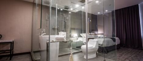 A modern hotel bathroom with a glass-enclosed shower, a toilet, and a sink.