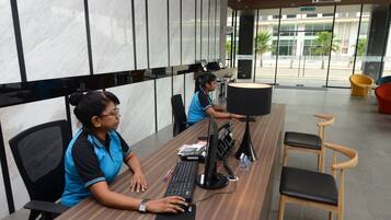 A modern office space with two employees at desks, equipped with computers and a large monitor.