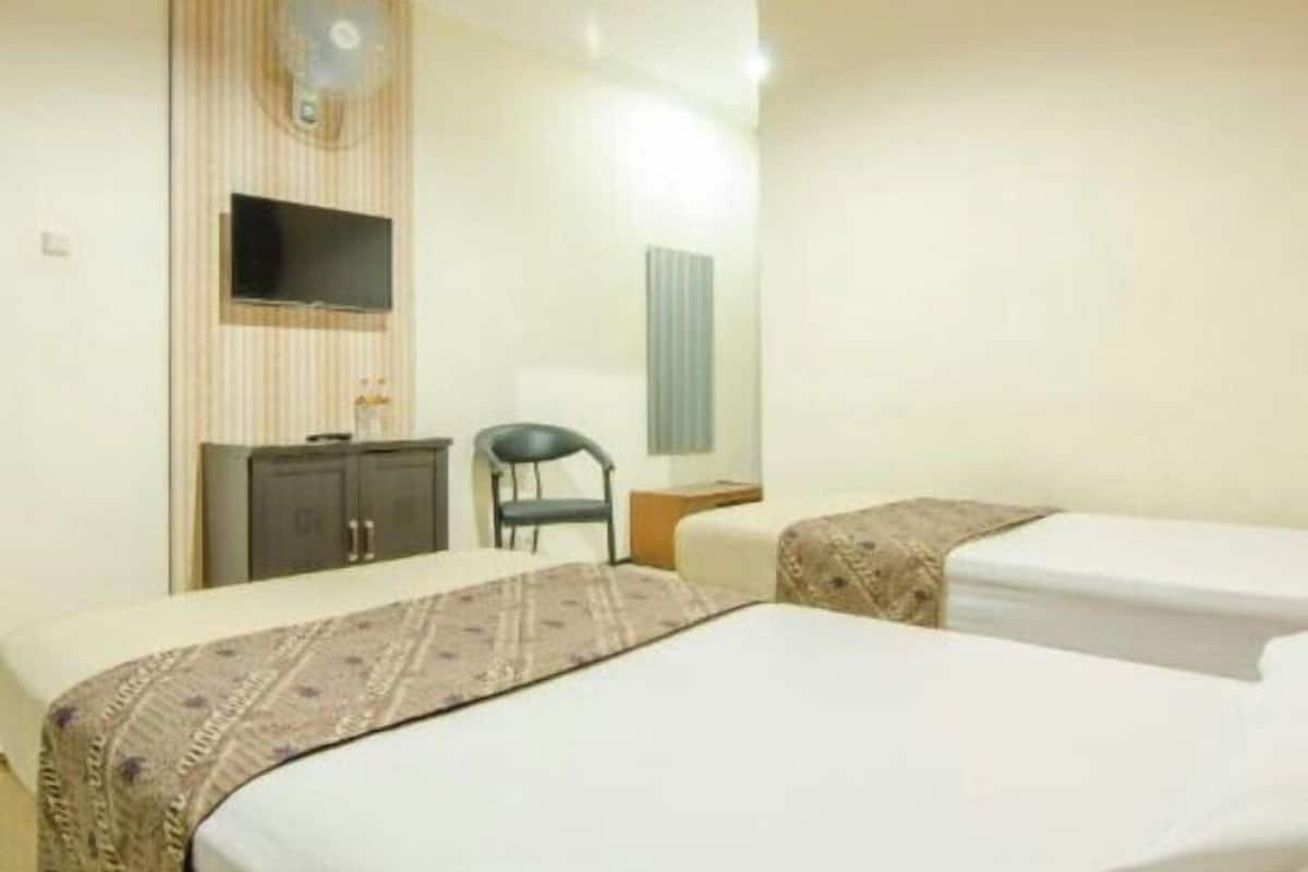 Habitación de hotel con dos camas, televisor, escritorio y una silla.