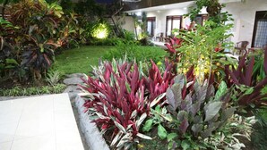 Un jardin bien entretenu, agrémenté de diverses plantes et doté d’un espace patio situé devant un immeuble avec balcon.